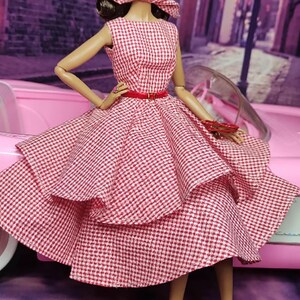 K&ouml;nnte beinhalten: Ein rot-wei&szlig; kariertes Kleid mit vollem Rock und rotem G&uuml;rtel. Das Kleid ist geschichtet und hat einen Vintage-Stil.
