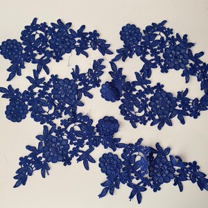 May include: Blue lace trim with a floral design. The lace is delicate and intricate, with a variety of different flower shapes and sizes.