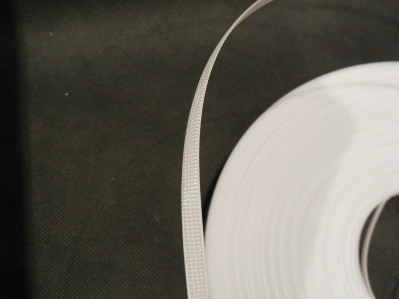 Puede incluir: Un rollo de fleje de pl&aacute;stico blanco, un tipo de material de embalaje utilizado para asegurar art&iacute;culos.