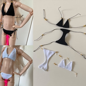 Może przedstawiać: Dwa komplety bikini: góra i dół. Jeden komplet jest czarny z złotymi akcentami, a drugi biały. Oba komplety są wykonane z tkaniny i mają regulowane ramiączka.