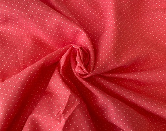 Peut inclure: Tissu de couleur corail avec un motif à pois blancs. Le tissu est plié et froissé, créant un aspect texturé. Les petits pois espacés uniformément offrent un design classique et ludique. Ce tissu convient à divers projets de couture.