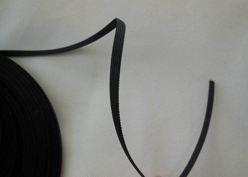 Puede incluir: Cord&oacute;n el&aacute;stico negro, enrollado en una bobina, con una longitud recta de cord&oacute;n que se extiende desde la bobina.