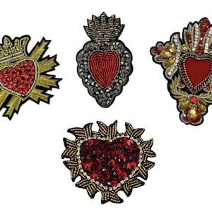 Puede incluir: Cuatro parches bordados para planchar que presentan un corazón rojo con adornos dorados y plateados. Los corazones están rodeados de varios diseños, incluyendo coronas, flores y rayos.