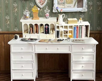 May include: A white desk with multiple drawers and a hutch, styled with miniature decorative items. The desk has a classic design with a series of drawers on each side. The hutch features compartments for organizing small items. Decorative elements include framed pictures and jars.