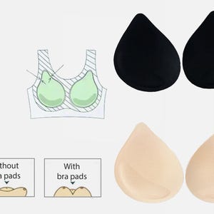 Puede incluir: Imagen de producto que muestra dos pares de almohadillas para sujetador. Un par es negro, el otro beige. La imagen también incluye diagramas que ilustran el uso de almohadillas para sujetador dentro de un sujetador, y texto que dice "Sin almohadillas" y "Con almohadillas".