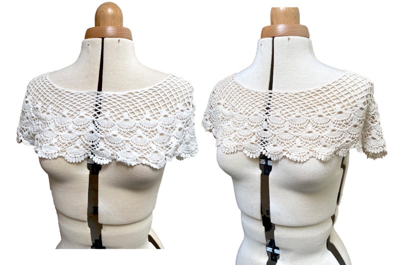 May include: White crochet lace collar with a scalloped edge. The collar is displayed on a white dress form.
