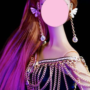 May include: A doll with long, flowing red hair wearing a gold chainmail top and dangling earrings with butterfly accents.