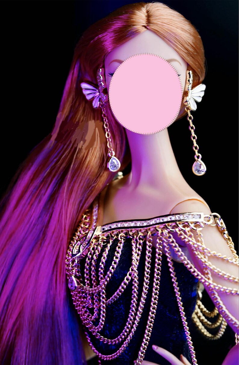 May include: A doll with long, flowing red hair wearing a gold chainmail top and dangling earrings with butterfly accents.