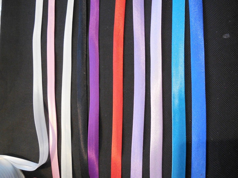 Puede incluir: Surtido de 10 cintas de raso de diferentes colores. Las cintas tienen todas el mismo ancho y est&aacute;n dispuestas en una fila de izquierda a derecha. Los colores son blanco, rosa, negro, morado, rojo, morado claro, blanco, azul, azul verdoso y azul.
