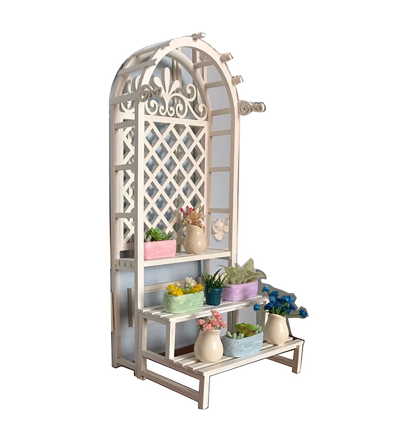 Puede incluir: Un soporte de plantas de madera blanca con un arco de enrejado y tres estantes. Los estantes est&aacute;n decorados con plantas en macetas y flores de varios colores, incluyendo rosa, azul y verde.