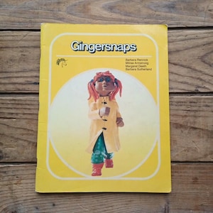 May include: A vintage book titled "Gingersnaps" with a yellow cover. The cover features a cartoon figure in a yellow coat, green pants, and red boots. The book's title is in a bold, blue font.