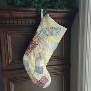 May include: A patchwork Christmas stocking with a yellow background and a variety of floral and geometric patterns in shades of blue, pink, and brown.