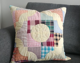 May include: A patchwork pillow with a yellow background and a circular design in the center. The pillow is made of various fabrics in shades of pink, blue, green, and red.