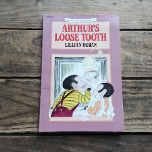 May include: A pink and white children's book titled "Arthur's Loose Tooth" by Lillian Hoban. The cover features an illustration of a boy looking in a mirror at his loose tooth.