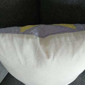 May include: A white pillow with a purple and yellow patchwork design on the back.