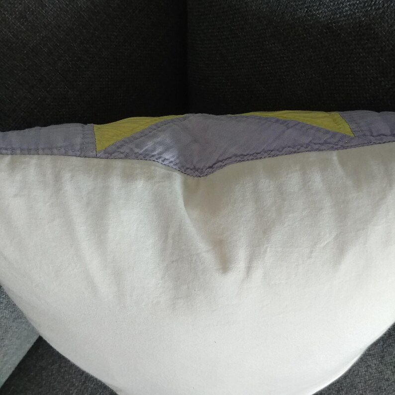 May include: A white pillow with a purple and yellow patchwork design on the back.