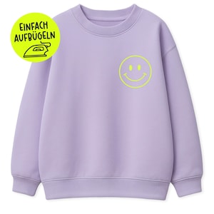 Könnte beinhalten: Ein fliederfarbenes Sweatshirt mit Rundhalsausschnitt und gerippten Bündchen. Auf der Vorderseite ist ein neongelbes Smiley aufgedruckt. Eine kreisförmige Grafik mit dem Text "EINFACH AUFBUGLEN" und einem Bügeleisensymbol befindet sich oben links.