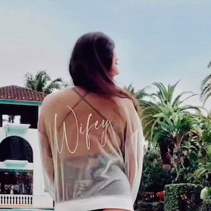 May include: A sheer white mesh top with the word "Wife" written in white script on the back.