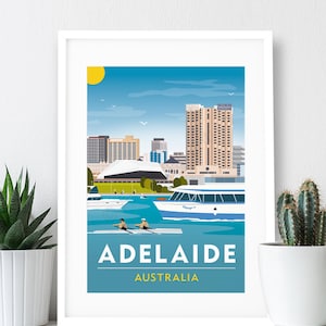 Puede incluir: Una impresión artística enmarcada que presenta una ilustración estilizada de Adelaida, Australia. La imagen muestra un paisaje urbano con barcos en el agua, dos remeros y el texto "ADELAIDE AUSTRALIA" en blanco sobre un fondo azul.