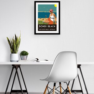 May include: A framed illustration of a woman sitting on a beach with a red and white polka dot hat, a white tank top, and orange shorts. The illustration is titled "Bondi Beach, New South Wales, Australia".