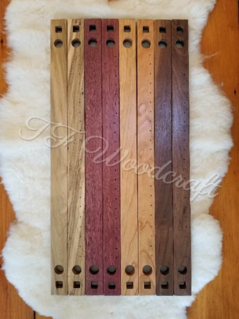 May include: Eight wooden dowels with holes drilled along their length. The dowels are in various shades of brown, red, and purple.