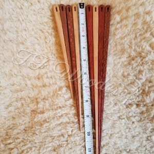 May include: Eight wooden knitting needles, some with a natural wood finish and others with a reddish brown stain. The needles are approximately 11 inches long and are arranged in a fan shape against a white fuzzy surface.