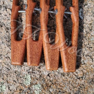 Könnte beinhalten: Fünf Holzstücke, die durch Metallschrauben verbunden sind und eine dekorative Wanddekoration bilden. Die Stücke sind rotbraun und haben eine glatte, polierte Oberfläche.