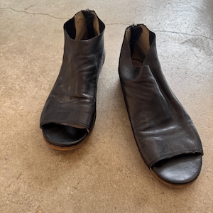 Puede incluir: Un par de sandalias de cuero negro de tacón abierto con cremallera en la parte posterior de cada zapato.