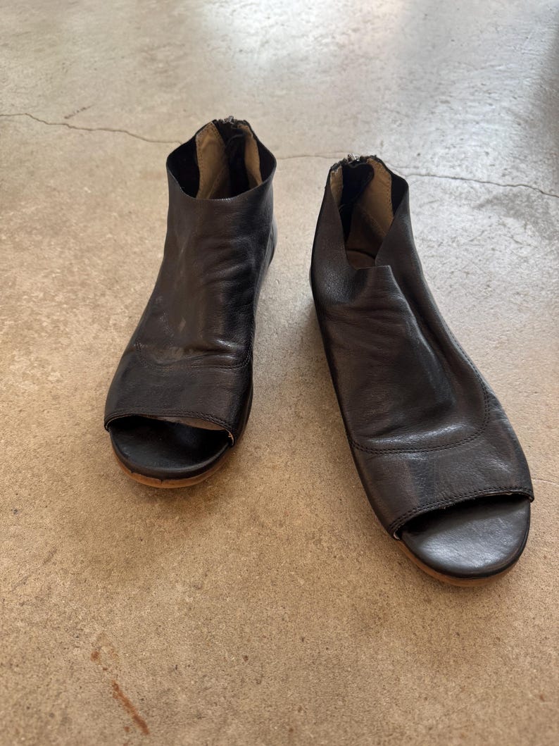 May include: A pair of black leather open-toe heeled sandals with a zipper on the back of each shoe.