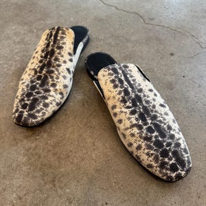 Puede incluir: Un par de zapatos de piel de serpiente negros y blancos con punta.