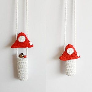 May include: Two crocheted mushroom-shaped zipper pouches with white cords. The larger pouch has a red mushroom top with white spots and a white pouch with a silver lighter inside. The smaller pouch has a red mushroom top with white spots and a white pouch.