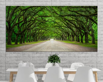 May include: A large rectangular canvas print depicting a tree-lined road. The trees form a tunnel of green foliage over a dirt road. The print is displayed above a white table with white chairs.