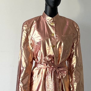 May include: A metallic pink and gold two-piece outfit with a long-sleeved jacket and a pleated skirt.