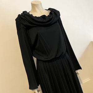 May include: A black long-sleeved dress with a cowl neck and a pleated skirt.