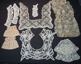 Puede incluir: Un surtido de cuellos y adornos de encaje antiguos en varias formas y diseños. La colección incluye delicadas piezas de encaje blanco y beige, que muestran patrones florales y geométricos. Las piezas están dispuestas sobre una superficie oscura, resaltando los intrincados detalles.