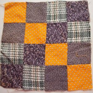 Pu&ograve; includere: Un quadrato patchwork composto da sedici quadrati di tessuto in vari modelli e colori. I colori includono giallo senape con pois bianchi, grigio con piccoli motivi floreali e quadri verdi e bianchi.