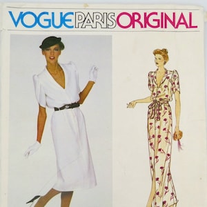 May include: A vintage Vogue Paris Original sewing pattern featuring two dress designs. One dress is a white, short-sleeved wrap dress with a black belt. The other is a floral print maxi dress. The pattern includes the Givenchy logo and the number 2165.