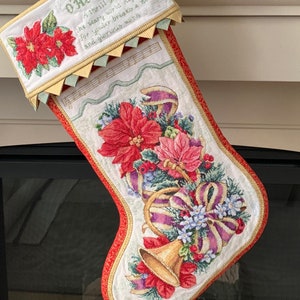 May include: A red and white Christmas stocking with a gold bell and a floral design. The stocking is embroidered with the words "O'Holy Night" and a verse of the song.