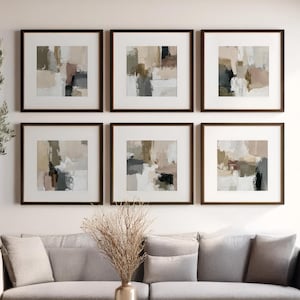 Può includere: Sei stampe artistiche astratte incorniciate in tonalità neutre di beige, grigio e marrone sono appese sopra un divano grigio. Un tavolino in legno e un albero di ulivo in vaso completano l'arredamento del soggiorno. L'opera è in stile moderno e minimalista.