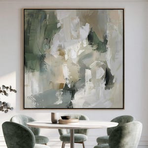 May include: A large square abstract painting featuring layered brushstrokes in shades of sage green, cream, white, and charcoal grey. The artwork is displayed on a white wall above a round white dining table surrounded by four sage green upholstered chairs.