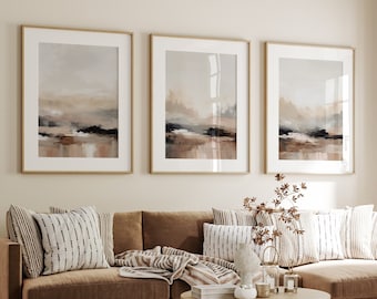 May include: A brown sectional sofa with a light brown throw blanket and several pillows. The sofa is in front of a wall with three framed abstract paintings. A wooden coffee table sits in front of the sofa.