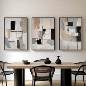 Puede incluir: Tres pinturas abstractas con formas geométricas en tonos grises, negros y beige. Las pinturas están enmarcadas en negro y colgadas en una pared blanca.
