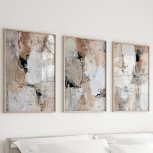 Könnte beinhalten: Drei gerahmte abstrakte Kunstwerke. Jedes Stück hat ein strukturiertes Design mit Beige-, Weiß-, Schwarz- und Brauntönen. Die Kunstwerke werden in hellfarbigen Holzrahmen präsentiert und bilden ein zusammenhängendes Set für die Wanddekoration.