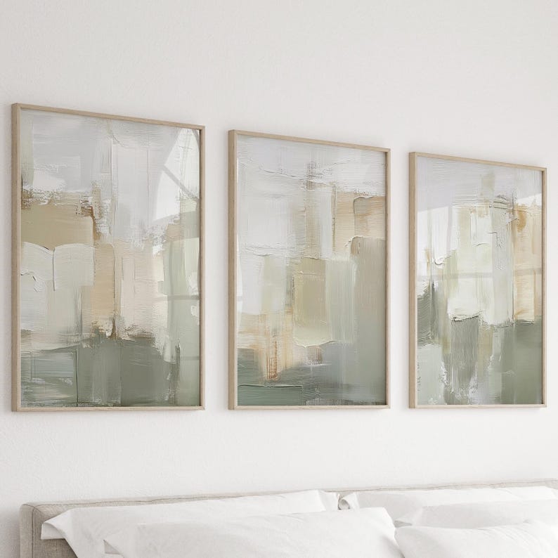 May include: Three framed abstract art prints. Each print features a textured, layered design in shades of white, beige, and green. The artwork is encased in a light-coloured wooden frame, creating a cohesive set for wall decor.