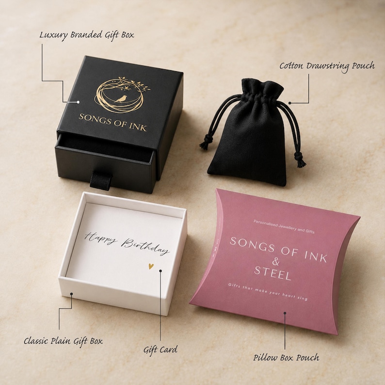 May include: A black luxury branded gift box with a gold bird logo and the text SONGS OF INK, a black cotton drawstring pouch, a white classic plain gift box containing a Happy Birthday gift card, and a mauve pillow box pouch labeled SONGS OF INK & STEEL.