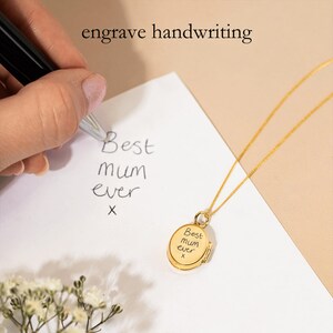 May include: A gold locket necklace with a handwritten message that reads "Best mum ever" on the front. The locket is open and the same message is engraved inside.