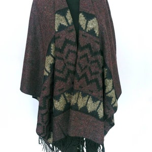 May include: A burgundy, black, and beige patterned poncho with fringe. The poncho is made of a soft, warm fabric and has a relaxed fit.
