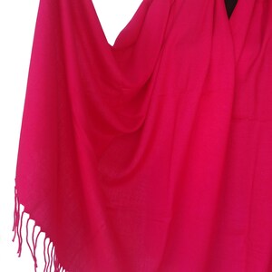 May include: A bright pink pashmina shawl with fringe on the edges.