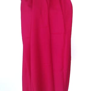 May include: A bright pink scarf with fringe on the ends. The scarf is draped over a mannequin.