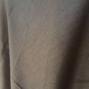 Puede incluir: Primer plano de una tela gris oscuro con un tejido texturizado sutil. La tela tiene una superficie lisa y uniforme y un acabado ligeramente brillante.
